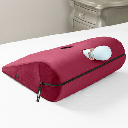 Aubergine Axis Toy Mount sitting on a bed with a white vibrator in the whole.