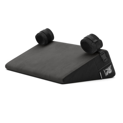 A black Bondage Wedge, Bedroom Furniture by Liberator with handcuffs on a white background.