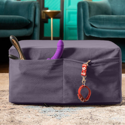 An Aubergine Center Stage ottoman, Bedroom Furniture by Liberator folded up showing toys stored in the pockets in a livingroom.