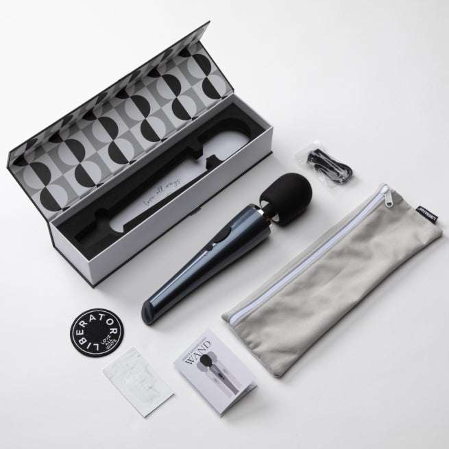 A black DeJour Vibrating Wand bedroom toy by Liberator showing what it comes with on a white background.