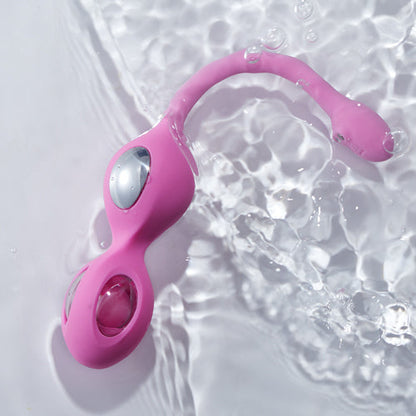 A pink Elektra-App-controlled E-Stim Kegel Training set laying in water against a white background.