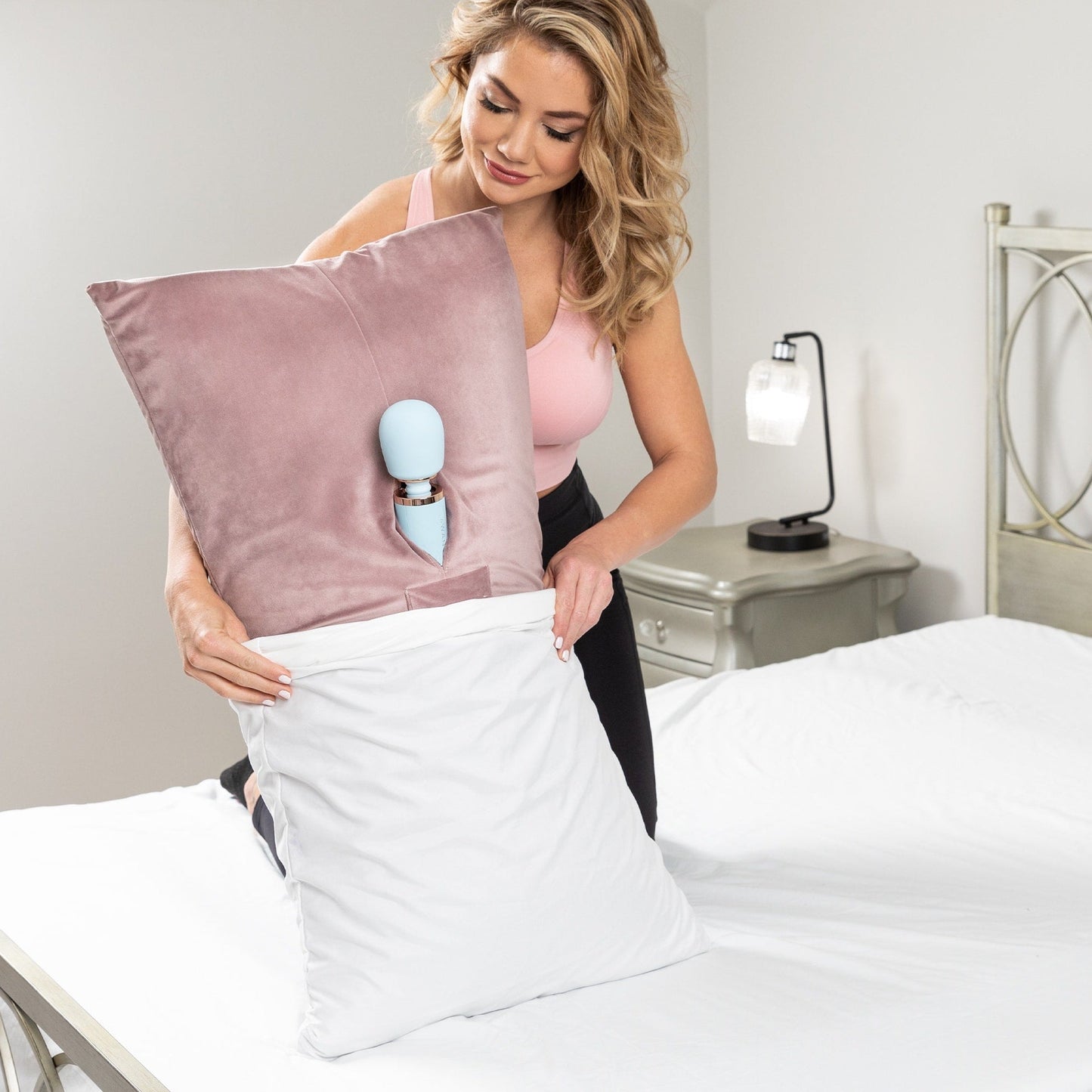A lady putting a rose colored Humphrey Toy Mount pillow, Bedroom Furniture with a toy in it into a white pillowcase.