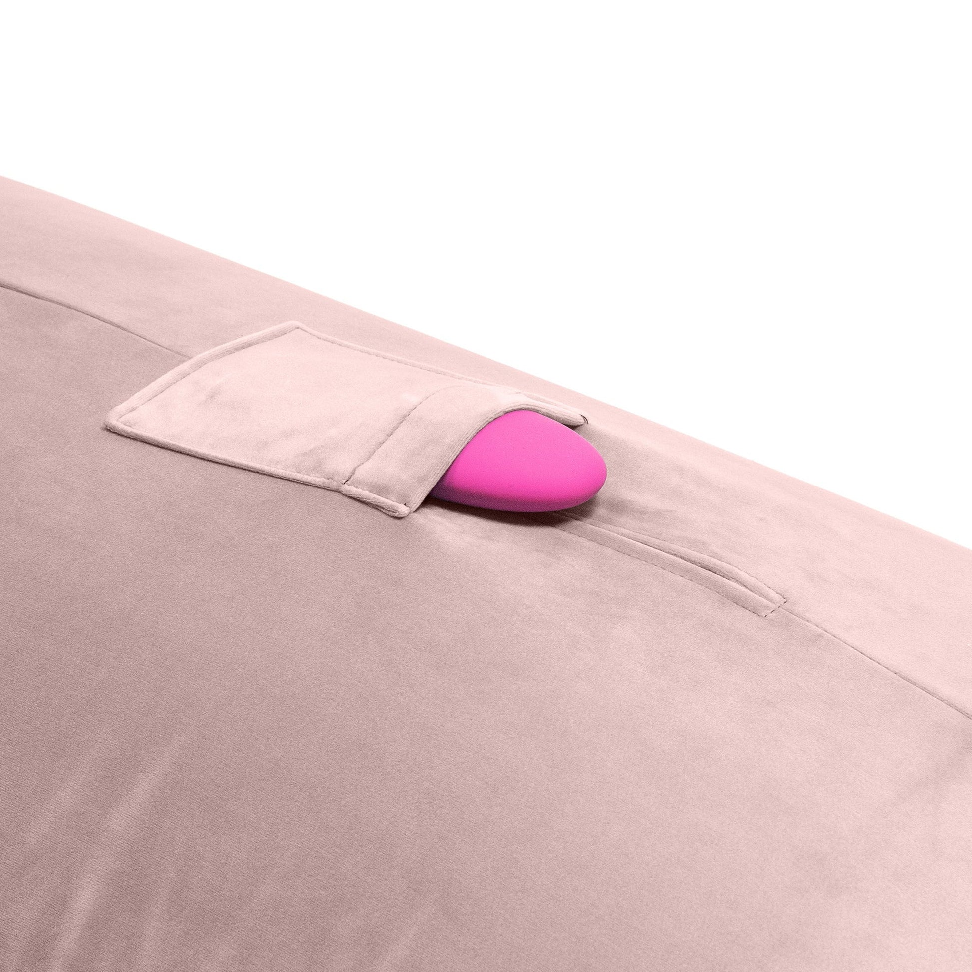 A close up of the toy pocket of a rose colored Humphrey Toy Mount pillow, Bedroom Furniture with a toy in it by Liberator against a white background.