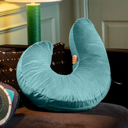 A blue Lune Snuggle curved Pillow, Bedroom Furniture by Liberator sitting on a couch with a toy in the pocket.