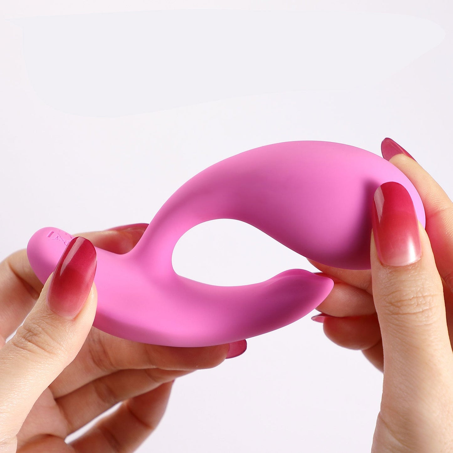 Hands holding a pale pink OLY 2 Pressure Sensing APP-enabled Wearable Clit & G Spot Vibrator against a white background.