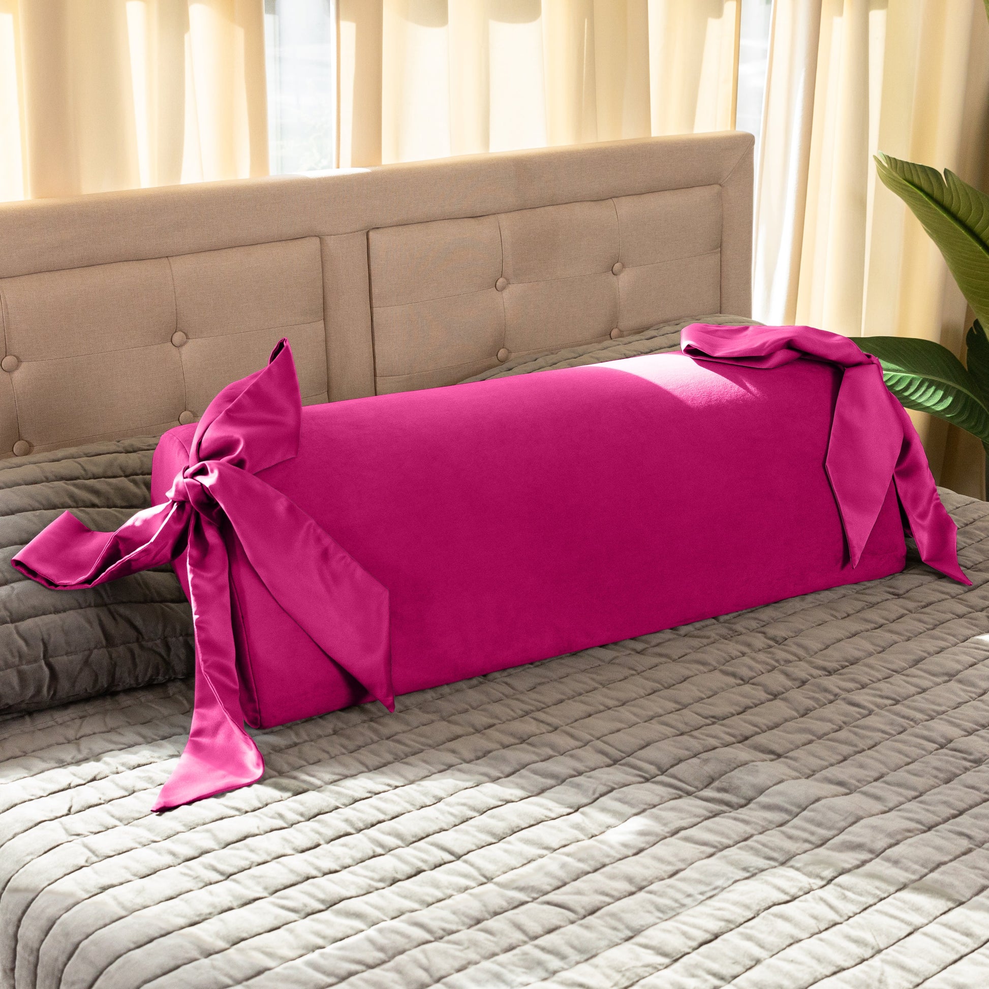 A pink Ravish Bondage Pillow, Bedroom Furniture by Liberator sitting on a bed.