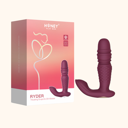 A purple Ryder Thrusting Vibrator against a white background sitting next to the box.