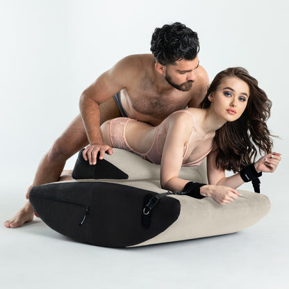 A couple on a buckwheat colored Scoop and wedge Valkyrie, Bedroom Furniture by Liberator with cuffs against a white background.