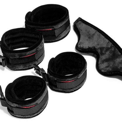 Four black cuffs and a blindfold for the Supervio Tantric Chaise bedroom funiture by Liberator against a white background.